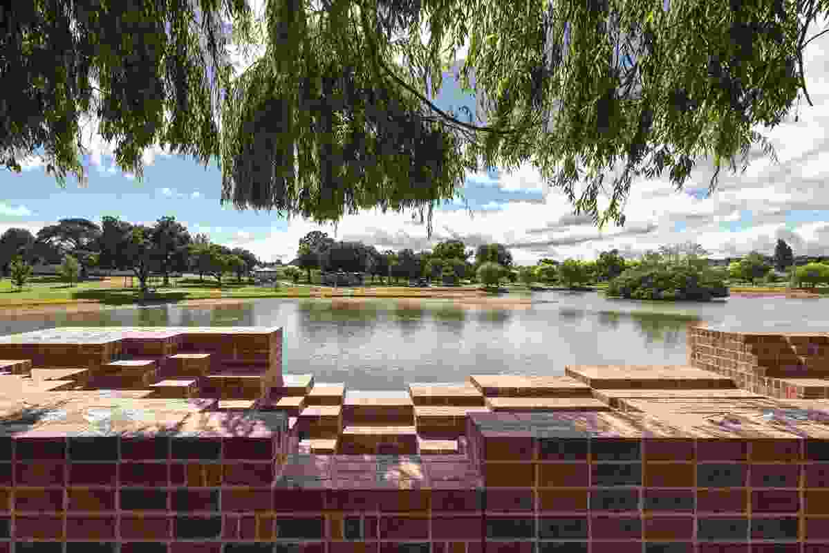 The view is framed by the voids in the brickwork and the willow tree.