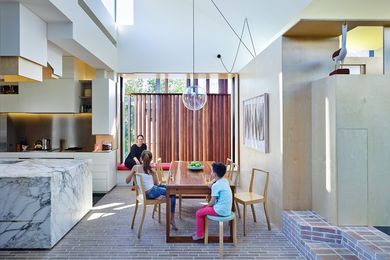 A luminous slab of marble forms the kitchen bench, contrasting with the robust timber and brick interior elements.