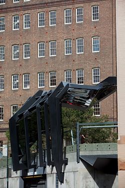 Oblique view of the canopy, “half-draped, half-clamped” between the podium and the building.