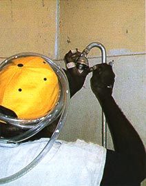 A local community survey fix worker completes the installation of a new shower rose. The plastic tube around the hat is to test that all floor wastes function well.