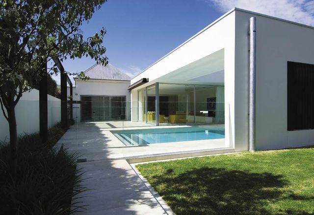 The white, rectilinear addition to the rear seamlessly abuts the existing house.