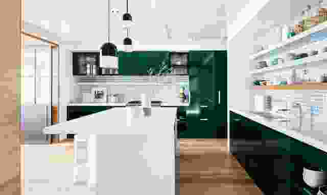 绿色搪瓷橱柜与宽敞舒适的厨房里的白色瓷砖形成对比，显得暗而丰富。