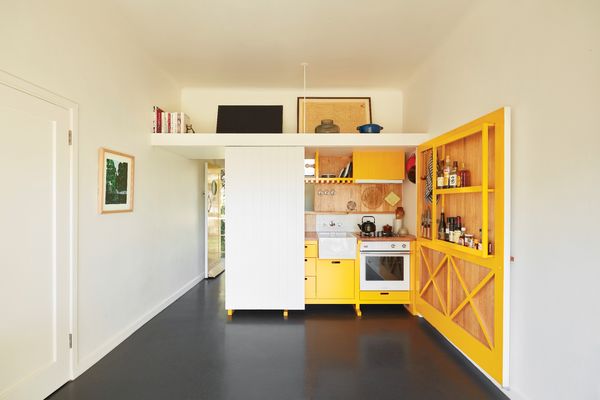 The splash of colour in the kitchen cabinetry was inspired by the bold yellow floor of Le Corbusier’s Cabanon. Artwork (L-R): Sally Ross; Minnie Pwerle.