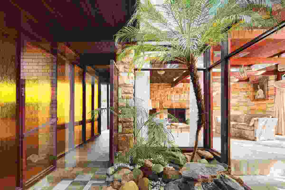 The formal living and dining spaces pinwheel around a courtyard rockery and palm garden.