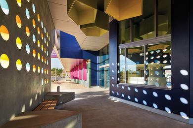 Perforations in the precast concrete verandah panels create patterns of light and shadow on the exterior walls and floor of the central waiting area.