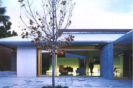 Overview from the main courtyard, looking back into the living and dining areas. The translucent boxes of the kitchen and storage unit define and light the space. The bedroom courtyard is beyond.