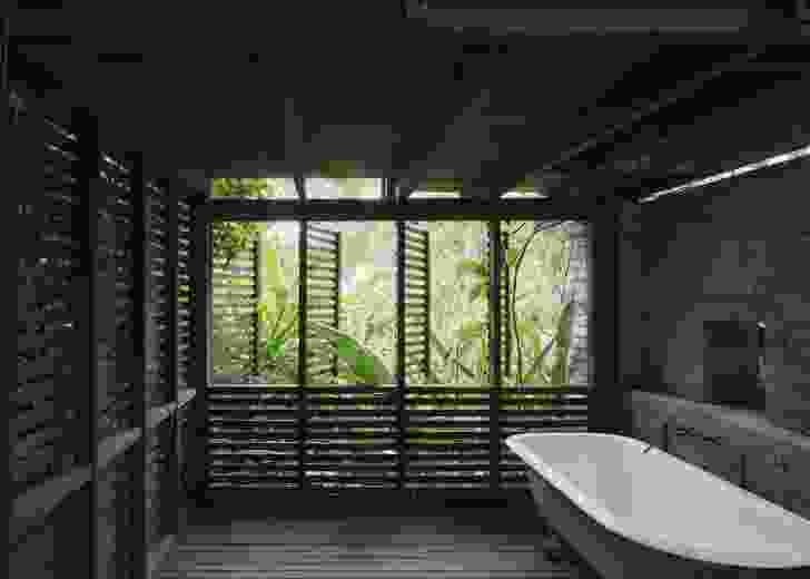 A screened outdoor bathroom is a nested bower, now wrapped in vines and subtropical plants.