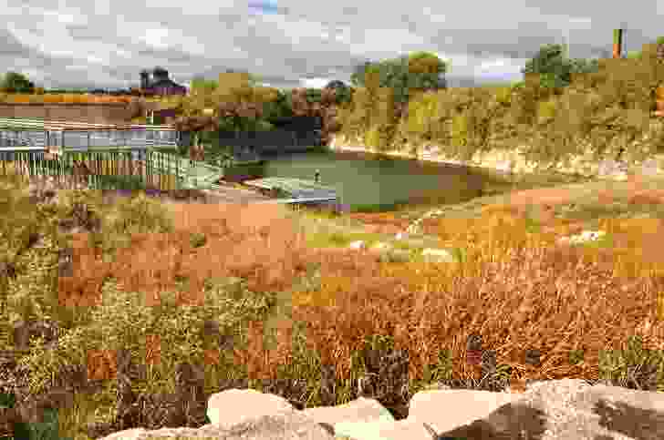 At Henry Palmisano Park, a steel walkway leads into the sloping site, offering views of the exposed quarry cliff face.