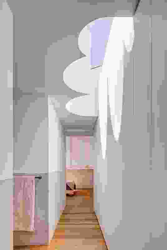 A dramatic “cloud light,” referencing the form of the original hallway arch, appears to float at the top of the stairs.