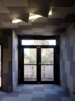 Inside the furnished interior. Carpet tiles cover the floor, walls and ceiling, fringing out around the fluorescent lights.