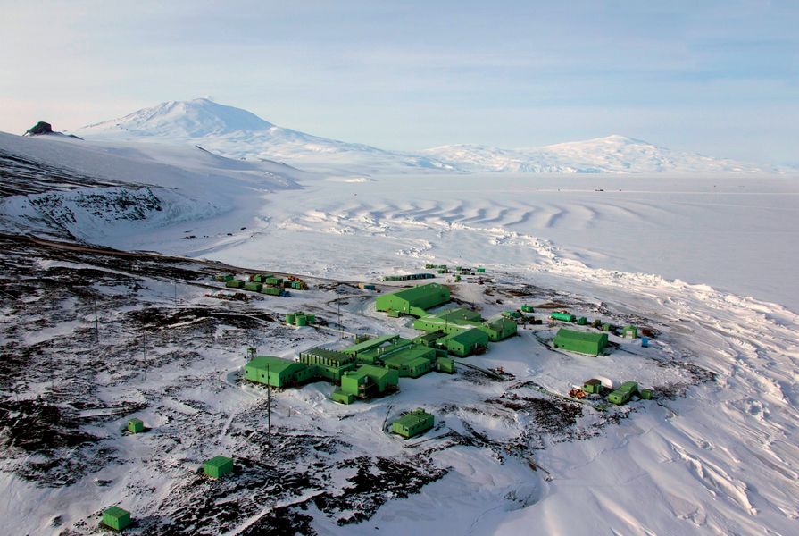 Scott Base with Mount Erebus in the background. There were differing accounts about why the buildings were painted green. A popular theory was that the Superintendent, Bob Thomson, liked Ireland's white cottages surrounded by green and reversed this combination for Scott Base.