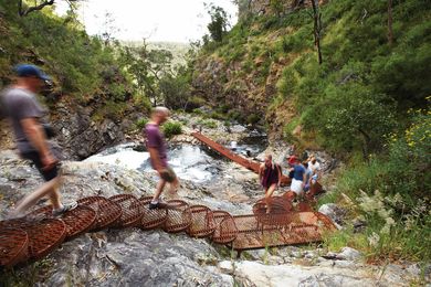 A cascading steel mesh staircase is bolted onto a rock face adjacent to the MacKenzie River.