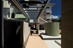  Looking along the pedestrian spine to the entry. The rainwater tanks, which service water-efficient toilets for each unit, also clearly express the project’s commitment to biophysical sustainability as well as social sustainability. Image: Graham Philip 