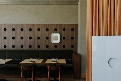 Perforated timber veneer wall panelling sets a datum for the entire venue . Artwork: Lucia Dohrmann.