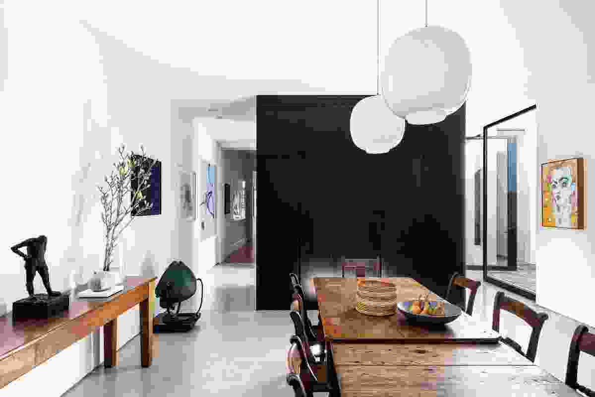 A large section of black joinery separates the dining and living areas from the kitchen.