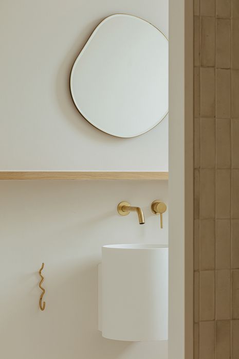 Curves in the basin, mirror and statement towel hook add subtle embellishment to the bathroom.