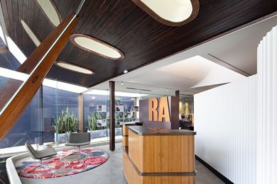 Large oval light wells punctuate the timbered ceiling of the entry foyer, illuminating project images that hang inside the glazing.