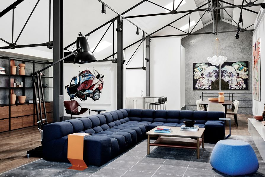 Beneath the warehouse’s steel trusses, over-scaled furniture gives structure to the open-plan living area. 