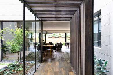 A low passage framed by dark-stained timber battens leads from the existing house to the rear extension.