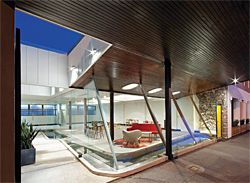 A narrow pedestrian arcade extends into the site. This leads to a second door, accessed via a steel grate that crosses over the pond.