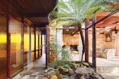The formal living and dining spaces pinwheel around a courtyard rockery and palm garden.
