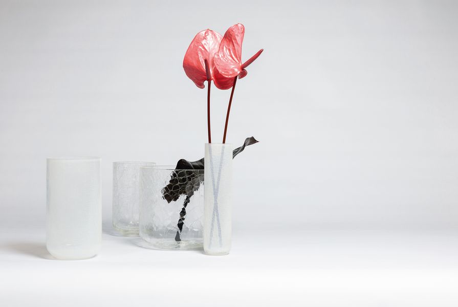 The Crackle Vases collection is a line of clear and milky glass vessels that appear as if they are fractured.