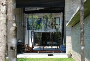 Gardenshell house – the shell of its living room helping to shield from the elevated mass transit rail to the rear, while making a pavilion of its living room between front garden and middle courtyard