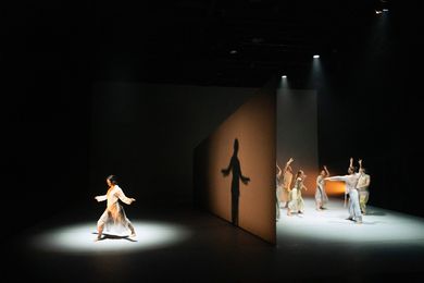 At the start of the performance, a monolithic, wedge-shaped wall slices the stage in two.