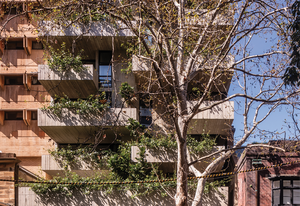 Located in the inner-Sydney suburb of Surry Hills, Woods Bagot’s residential and retail building presents a memorable facade of staggered concrete forms and dense foliage.