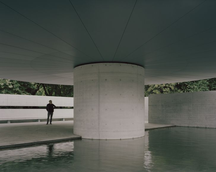 A large-spanning parasol supported a concrete circular concrete column partially shelters the enclosure.