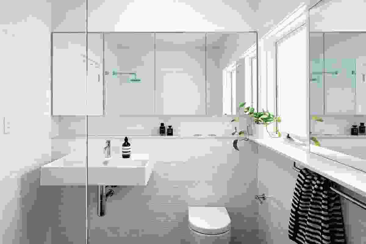 The bathroom’s minimalist aesthetic is emphasized by an all-white palette.