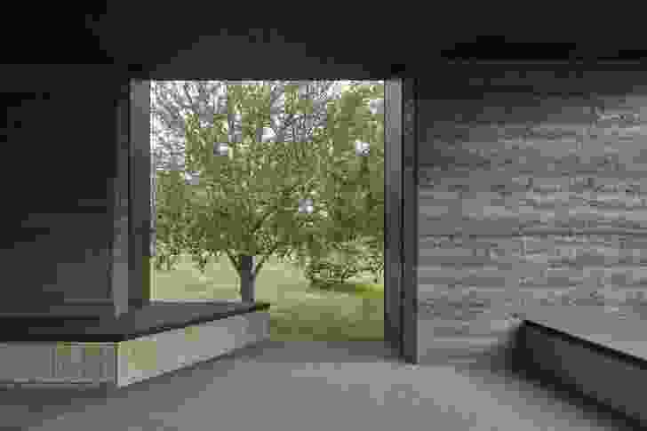 A window on the southern side of the home incorporates built-in seating facing the trees.