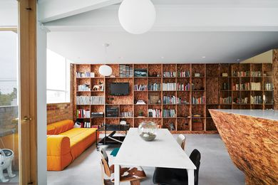 The southern wall is lined with a floor-to-ceiling bookshelf that matches the kitchen joinery.