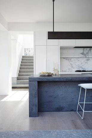 V-groove panelling conceals the fridge, pantry and storage, allowing the sculptural concrete island to take precedence in the kitchen.