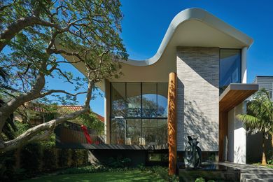 Otherwise rectilinear in form, the house features a curved roof and balcony that trace the canopy of a large jacaranda tree. Sculpture: Blaze Krstanoski-Blazeski.
