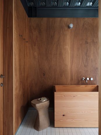 The ground-floor bathroom contains a custom timber bath.  Side table: Tanika Jellis.