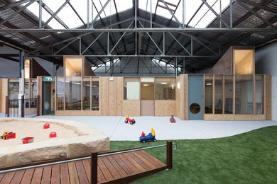 An indoor landscape unfolds beneath the pitched roofs and steel trusses of the warehouse.
