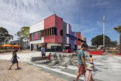 Visitors of all ages frolic in the striking and tactile water feature that foregrounds the hub building’s undulating and colourful west face.