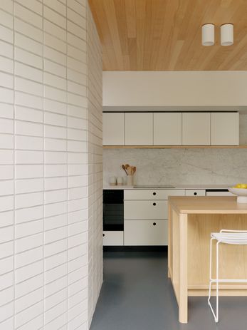 The kitchen and informal dining area features an angled glazed brick wall, designed to ricochet natural light into the space.