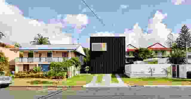When viewed from the street, the house appears as a dark box clad in compressed fibre cement sheeting and striped with battens.
