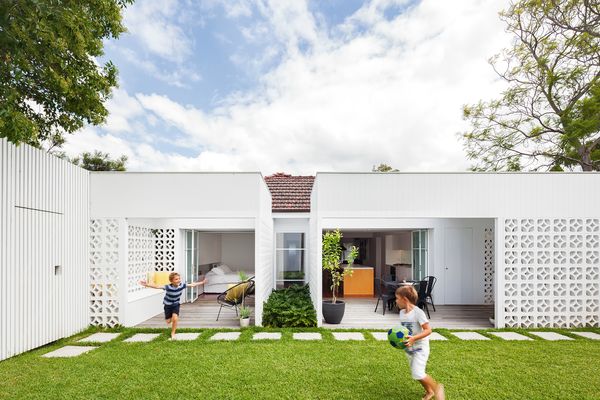 A gentle but dramatic transformation has taken place at the rear of a red brick home, with breezeblock walls creating outdoor rooms that open onto the yard.