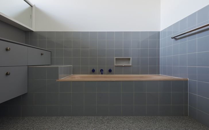 The peach bath has been overstated by the introduction of new electric blue faucets, and the beige vinyl floor has been replaced with blue-gray terrazzo.