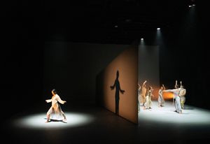At the start of the performance, a monolithic, wedge-shaped wall slices the stage in two.