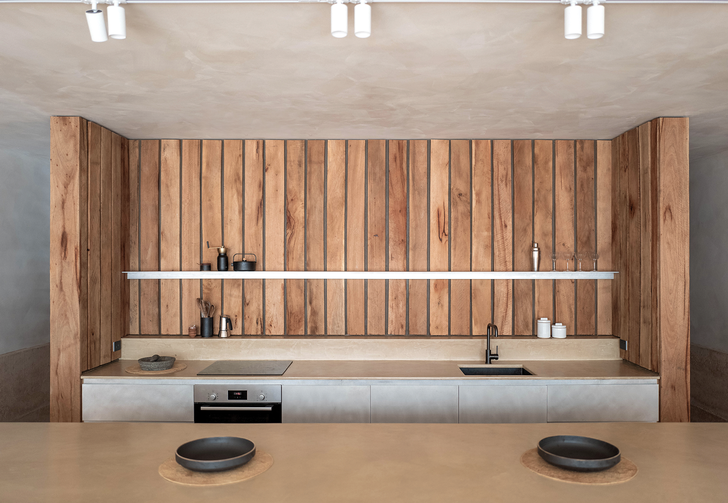 A timber wall containing the kitchen forms a bookend to the living spaces.