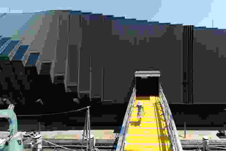 A yellow ramp, reminiscent of a gangway used to board and disembark from a ship, provides a connection from the Waterfront Pavilion to one of the vessels.
