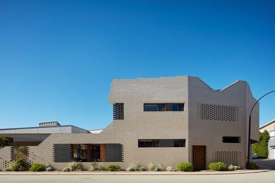 The new house abuts the street, with a stepped brick skin of varying porosity and thickness.
