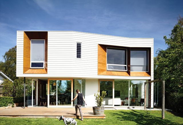 A two-storey extension at the rear of the site adds a solid, weatherboard form hovering above a level of full-height glazing.