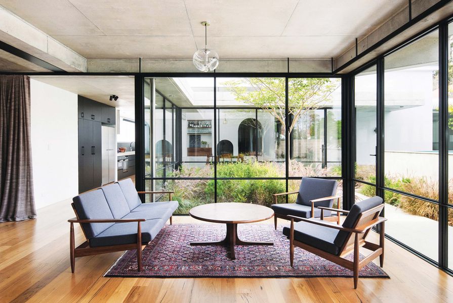 A courtyard erupting with billowing grasses draws in light and offers views through the living room to the dining area.