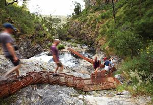 A cascading steel mesh staircase is bolted onto a rock face adjacent to the MacKenzie River.
