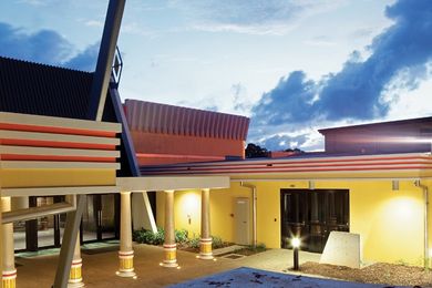 The entrance is flanked by two existing inclined concrete “buttresses.” A canopy appears supported by five columns.